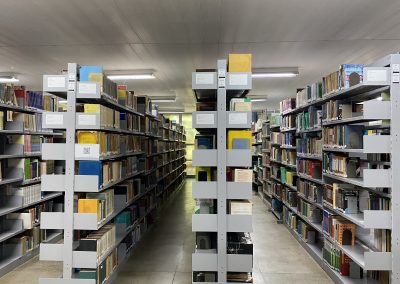 Acervo BEE - Biblioteca da Escola de Engenharia e do Instituto de Computação. Na foto: quatro estantes na cor cinza contendo os livros do acervo.